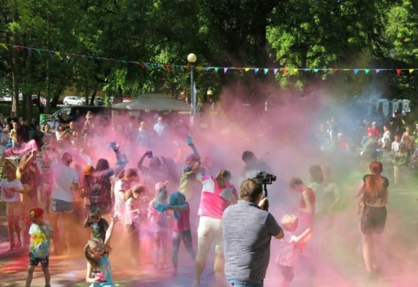 Dzień Dziecka w parku miejskim. Kolory Holi, Dzieci i dorośli przy muzyce rzucają w g&oacute;rę kolorowymi proszkami, potem wszyscy uczestnicy zabawy są kolorowi.