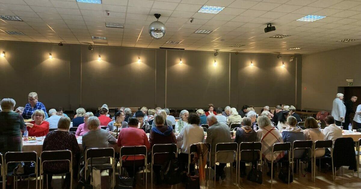 Spotkanie opłatkowe, wszyscy zgromadzeni siedzą przy stołach.