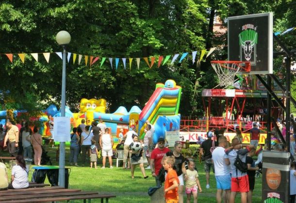 Dzieci w parku, w tle dmuchańce i kosz do gry w koszyk&oacute;wkę