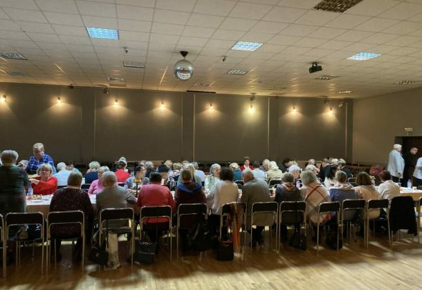 Spotkanie opłatkowe, wszyscy zgromadzeni siedzą przy stołach.