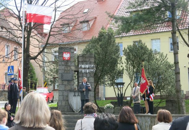 Burmistrz Miasta w trakacie przemowy, po bokach stoją sztandary.