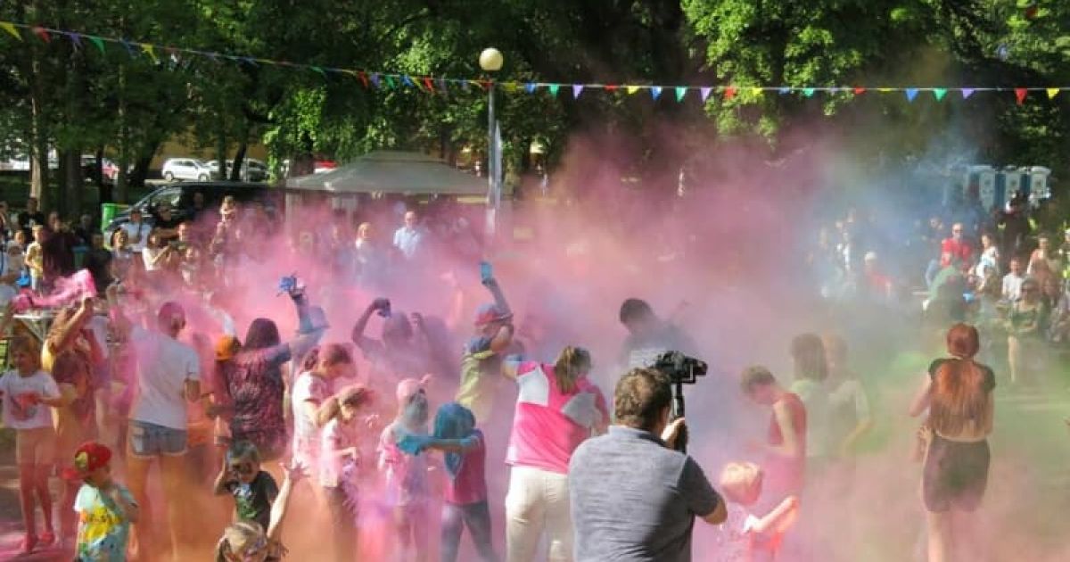 Dzień Dziecka w parku miejskim. Kolory Holi, Dzieci i dorośli przy muzyce rzucają w g&oacute;rę kolorowymi proszkami, potem wszyscy uczestnicy zabawy są kolorowi.