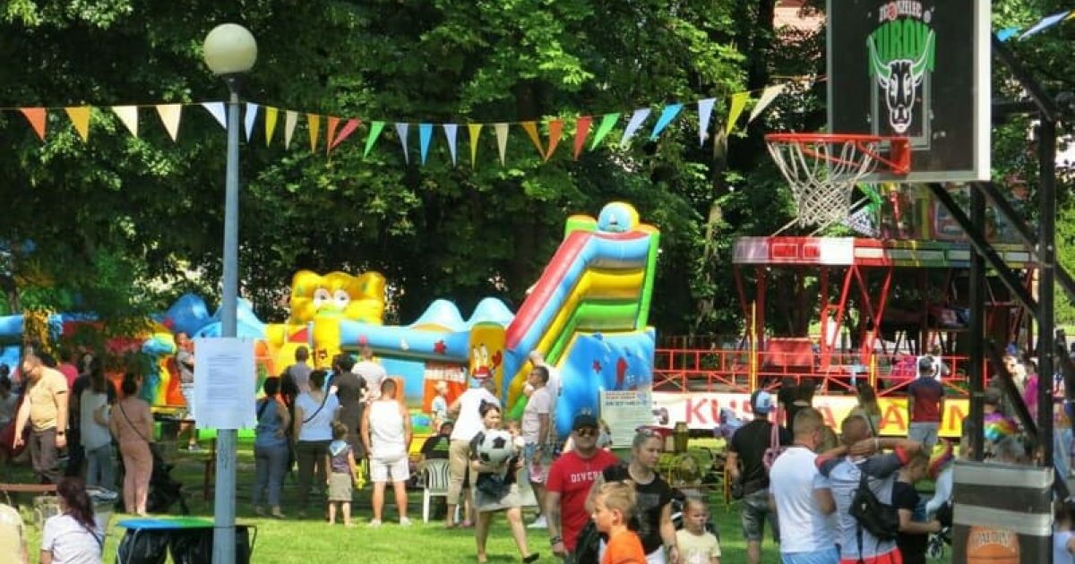 Dzieci w parku, w tle dmuchańce i kosz do gry w koszyk&oacute;wkę