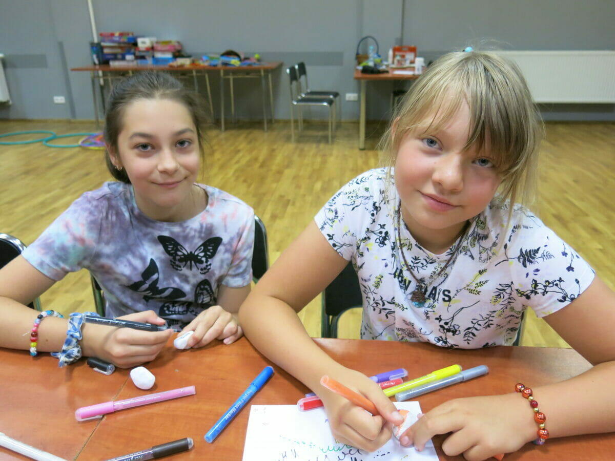Dziewczynki podczas zajęc plastycznych malują kamyki szczęścia.