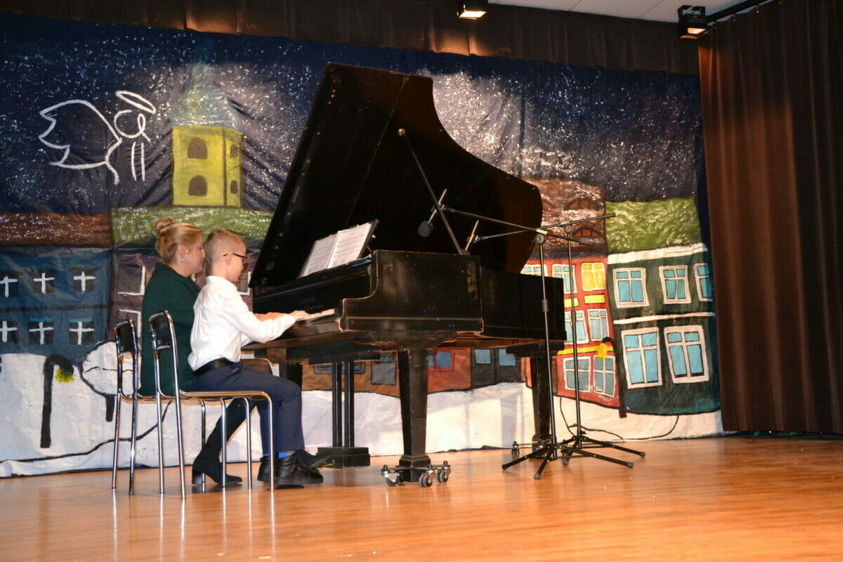 Koncert Bożonarodzeniowy. Gra na fortepianie przez chłopca, ucznia i panią nauczycielkę.