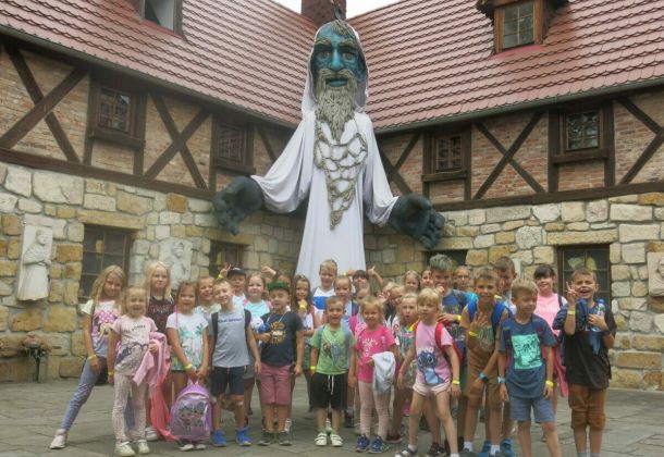 Wyjazd dzieci podczas akcji wakacyjnej do Magicznej Pławnej. Na zdjęciu grupa dzieci w tle postać ducha gór.
