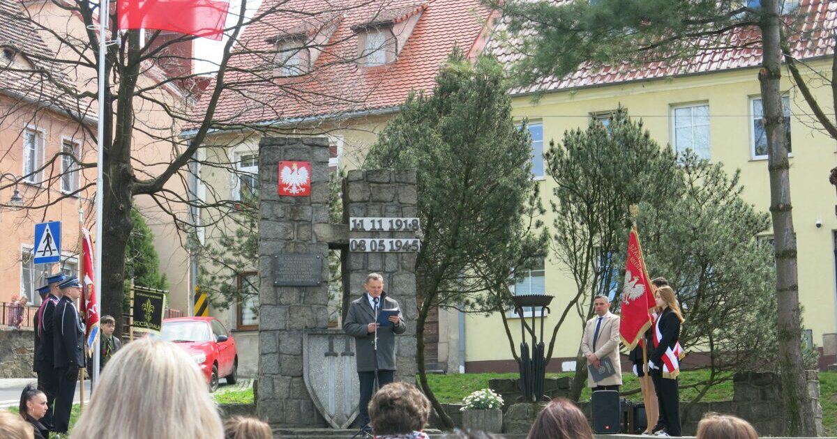 Burmistrz Miasta w trakacie przemowy, po bokach stoją sztandary.