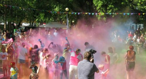 Dzień Dziecka w parku miejskim. Kolory Holi, Dzieci i dorośli przy muzyce rzucają w górę kolorowymi proszkami, potem wszyscy uczestnicy zabawy są kolorowi.