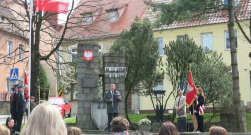 Burmistrz Miasta w trakacie przemowy, po bokach stoją sztandary.